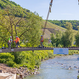 Arbeiter auf der Heppinger Brücke vor malerischer grüner Landschaft.