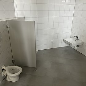 Zwei Toiletten und ein Waschbecken stehen im Raum.