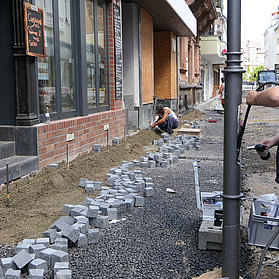 Arbeiter verlegt Kabel entlang einer Straßenlaterne.