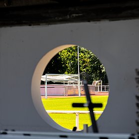 Blick durch eine runde Öffnung auf das noch im Bau befindliche Apollinarisstadion im Stadtteil Bad Neuenahr.