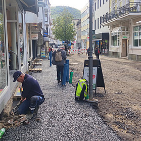 Arbeiter und Besucher in der neu asphaltierten Poststraße.