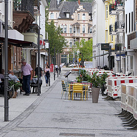 Blick auf geöffnete Läden, Cafés und Restaurants mit kleinen Baustellen auf der rechten Seite.
