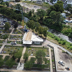 Aussegnungshalle am Friedhof Ahrweiler mit angrenzendem Fluss im Stadtteil Ahrweiler, umgeben von Ruhestätten und Grünflächen.