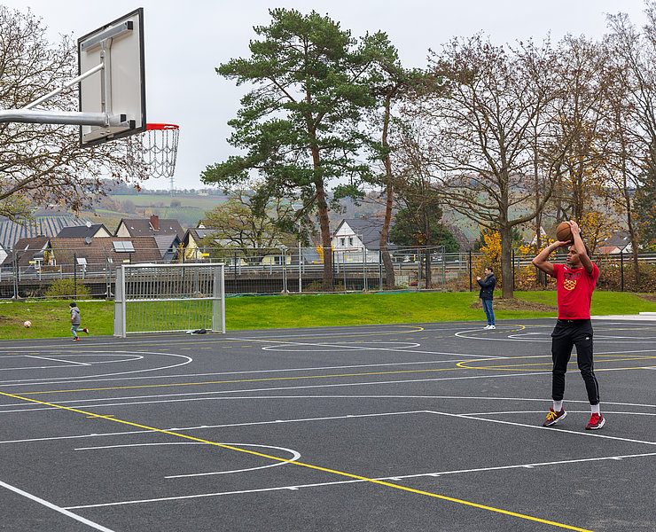 Sportplatz mit Basketballkorb und Spieler
