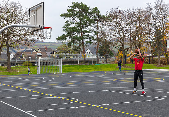 Sportplatz mit Basketballkorb und Spieler