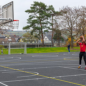 Sportplatz mit Basketballkorb und Spieler