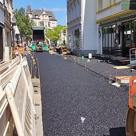 Mithilfe eines Großgerätes wird die Straße frisch asphaltiert.