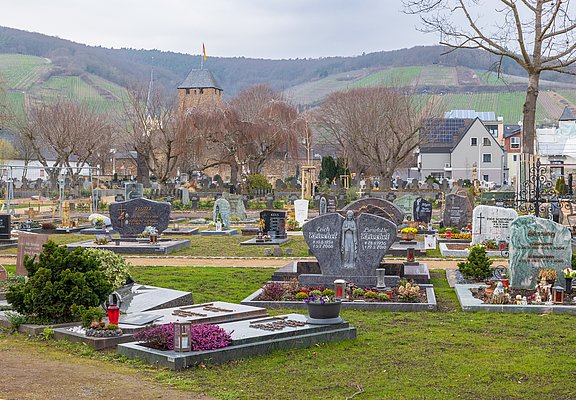 Blick über den Ahrtor-Friedhof im Stadtteil Ahrweiler mit historischen Gebäuden und Weinbergen im Hintergrund.