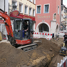 Offene Baustele mit Bagger und Arbeitern.