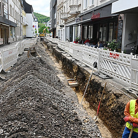 Arbeiter mit Warnweste und Helm steht in einem Graben entlang der Poststraße.
