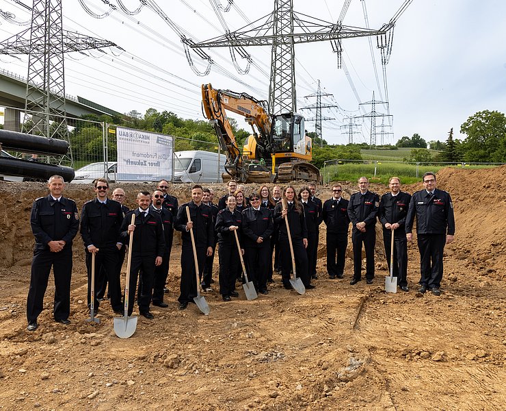 Feuerwehr Heppingen beim Spatenstich für das neue Feuerwehrhaus im Stadtteil Heppingen, Baustelle und Bagger im Hintergrund.