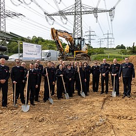 Feuerwehr Heppingen beim Spatenstich für das neue Feuerwehrhaus im Stadtteil Heppingen, Baustelle und Bagger im Hintergrund.