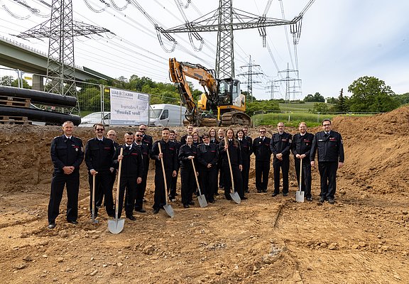 Feuerwehr Heppingen beim Spatenstich für das neue Feuerwehrhaus im Stadtteil Heppingen, Baustelle und Bagger im Hintergrund.