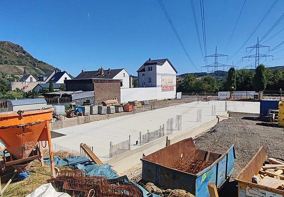 Fundament des Neubuas neben grünen Hügeln und Wohnhäusern