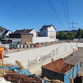 Fundament des Neubuas neben grünen Hügeln und Wohnhäusern