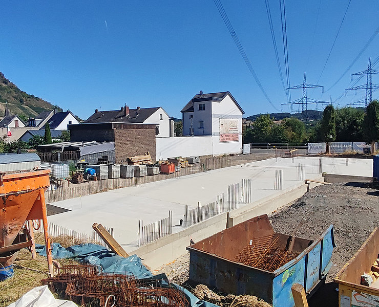 Fundament des Neubuas neben grünen Hügeln und Wohnhäusern