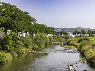 Idyllischer Blick auf den Stadtteil Bachem in Bad Neuenahr-Ahrweiler entlang eines ruhigen Flusslaufs.
