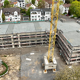 Luftaufnahme des Rohbaus mit Baukran Vordergrund.