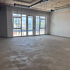 Blick in den Rohbau eines Raums mit großen Fenstern.