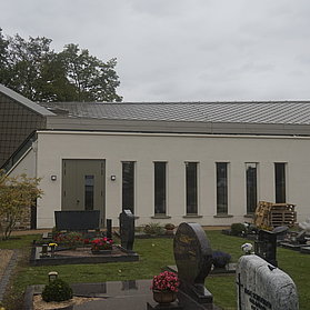 Aussegnungshalle auf dem Friedhof Ahrweiler im Stadtteil Ahrweiler als städtisches Gebäude in moderner Bauweise. Im Vordergrund sind Gräber zu sehen.