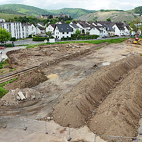 Baustelle für das neue Feuerwehrhaus im Stadtteil Ahrweiler mit umliegenden Wohnhäusern und grünen Hügeln.