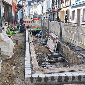 Offene Baustelle mit Zementeimer auf er linken und Bauzäunen auf der rechten Seite.