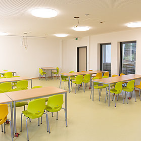 Moderner, heller Klassenraum der Aloisius-Grundschule in Ahrweiler, frisch im Bau mit bunten Stühlen und großen Fenstern.