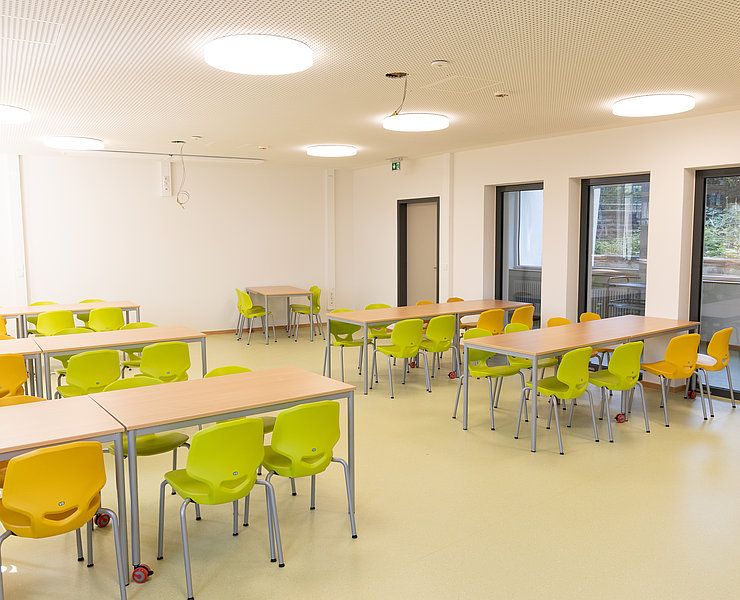 Moderner, heller Klassenraum der Aloisius-Grundschule in Ahrweiler, frisch im Bau mit bunten Stühlen und großen Fenstern.