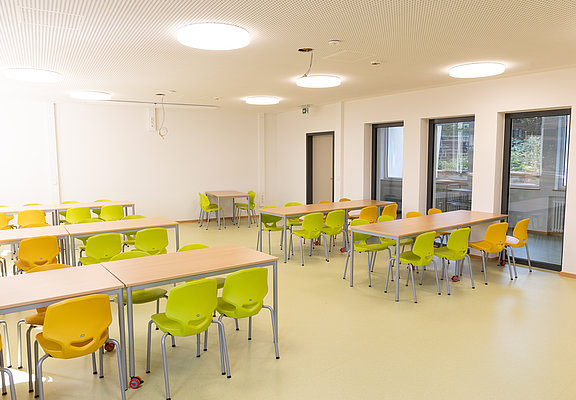 Moderner, heller Klassenraum der Aloisius-Grundschule in Ahrweiler, frisch im Bau mit bunten Stühlen und großen Fenstern.