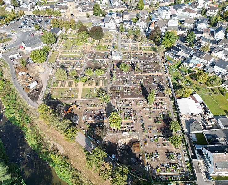Luftaufnahme des Ahrtor-Friedhofs in Ahrweiler, umgeben von Wohnhäusern und nahe dem Flussufer.