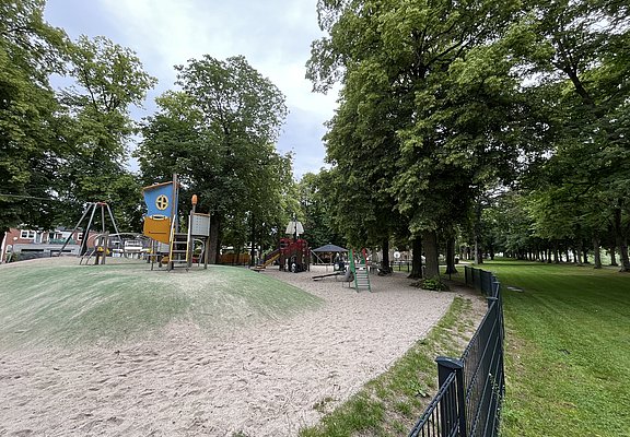 Klettergerüste und Schaukeln umgeben von Sand.