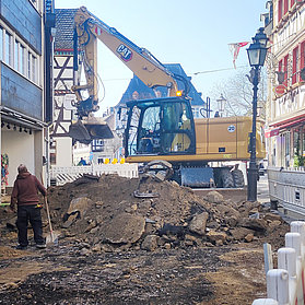 Offene Baustelle mit Bagger im Hintergrund.