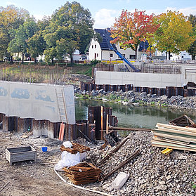 Bau der Bachemer Brücke im Stadtteil Bachem mit sichtbaren Betonpfeilern und Baumaterialien am Flussufer.