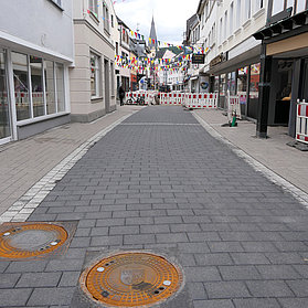 Blick durch die neu gepflasterte Niederhut mit Bauzäunen am Ende.