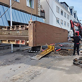 Ein Kran hebt ein schweres Bauteil über die Baustelle.