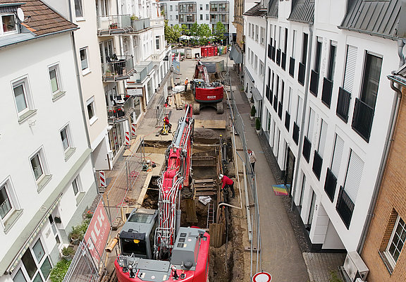 Bagger arbeiten an offener Straße zwischen Wohnhäusern