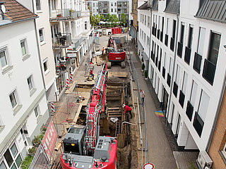 Bagger arbeiten an offener Straße zwischen Wohnhäusern