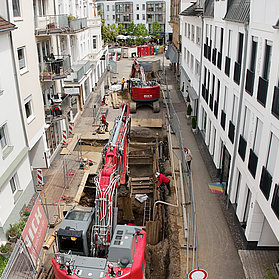 Bagger arbeiten an offener Straße zwischen Wohnhäusern