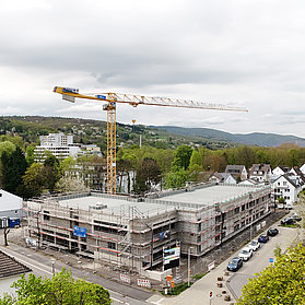 Über den Rohbau ragt ein großer gelber Baukran.