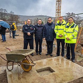 Beteiligte der Grundsteinlegung posieren vor der Baustelle.