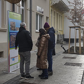 Einwohnerinnen und Einwohner vor einem Infoplakat in der Poststraße.
