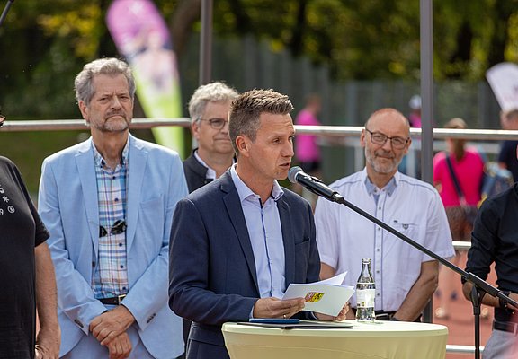 Der Bürgermeister hält eine Begrüßungsrede umgeben von Vertretern der Stadt und der Sportvereine