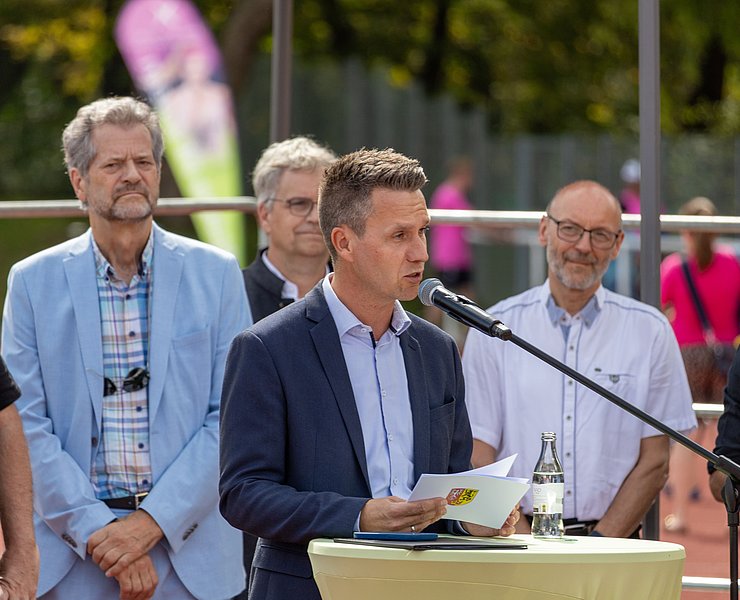 Der Bürgermeister hält eine Begrüßungsrede umgeben von Vertretern der Stadt und der Sportvereine