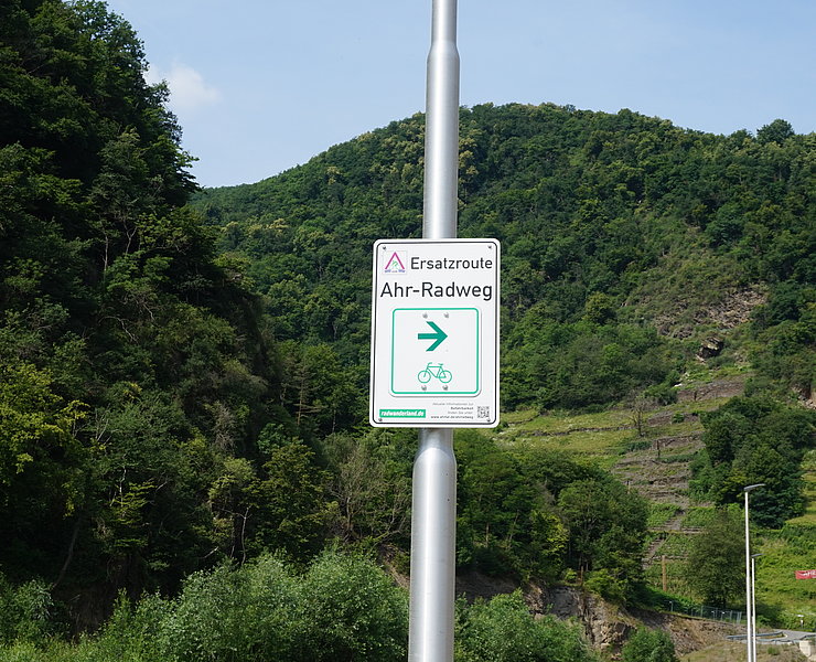 Ersatzroute Ahr-Radweg in Bad Neuenahr-Ahrweiler mit Wegweiser vor grünem Bergpanorama,