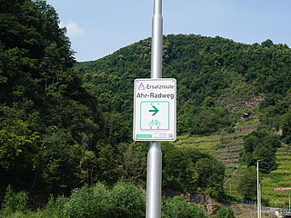Ersatzroute Ahr-Radweg in Bad Neuenahr-Ahrweiler mit Wegweiser vor grünem Bergpanorama,