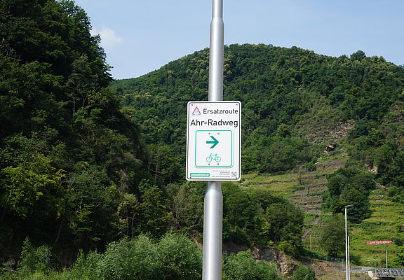 Ersatzroute Ahr-Radweg in Bad Neuenahr-Ahrweiler mit Wegweiser vor grünem Bergpanorama,