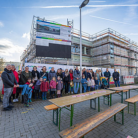 Bunte Farben auf einem Banner hängen vor dem Gerüst des Kita-Neubaus