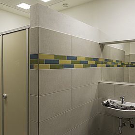 Zwei Toiletten-Kabinen, ein Waschbecken und ein Spiegel
