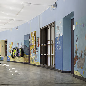 Flur der Aloisius-Grundschule Ahrweiler im Stadtteil Ahrweiler mit kindgerechten Wandmalereien und Garderoben.