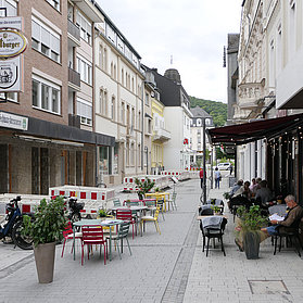 Blick in die Poststraße mit Gästen, die in der geschmückten Außengastronomie sitzen.